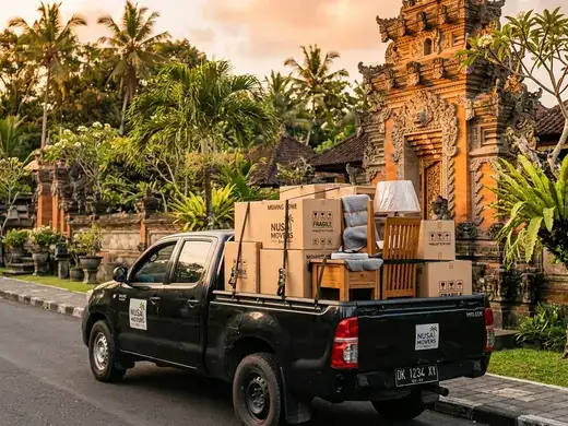 Pickup truck loaded with boxes on a Bali street with traditional temple gate